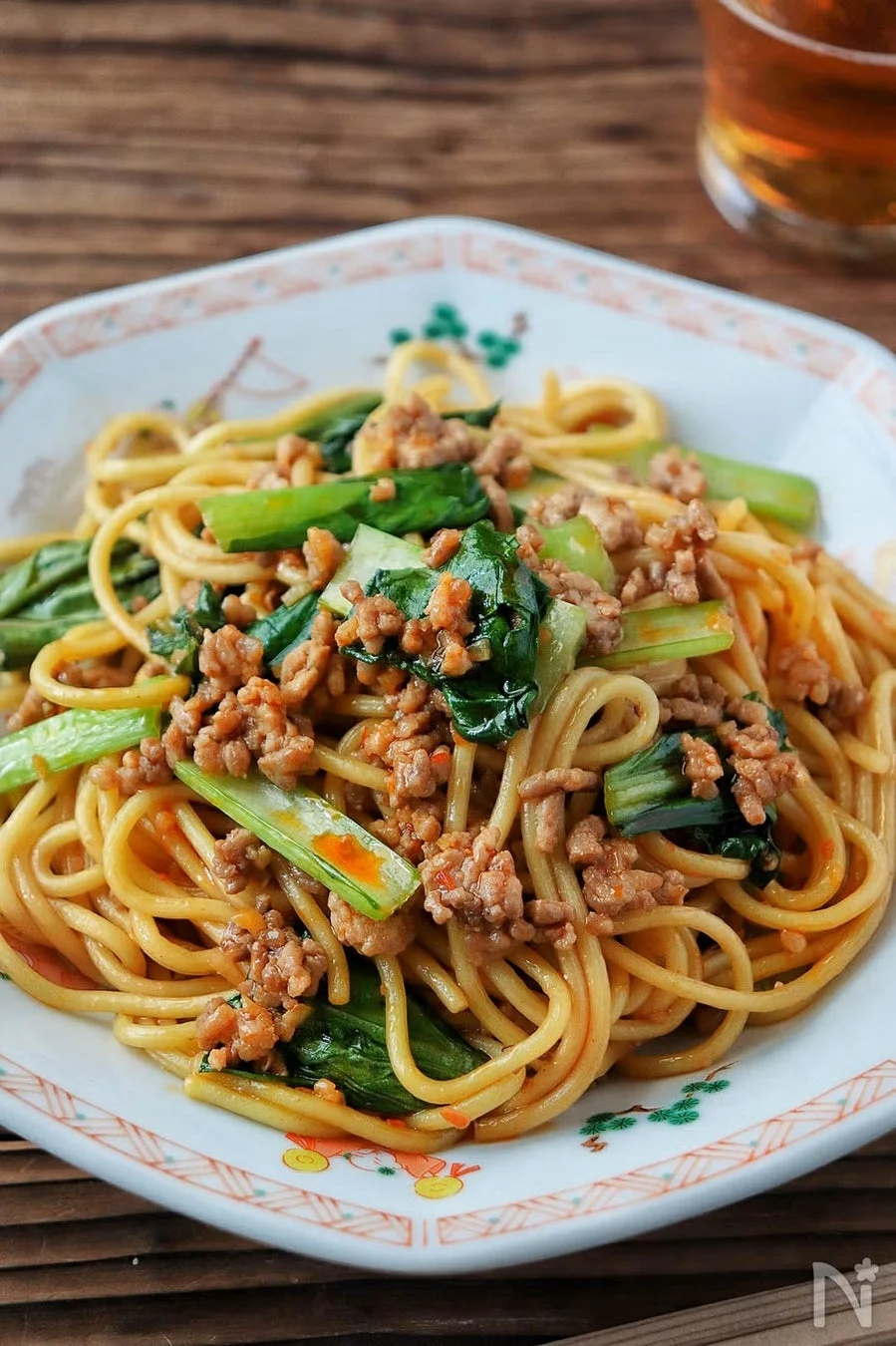 挽肉と青菜がたっぷり入った中華風の炒め麺が、模様の入った白い皿に盛られています。香ばしい色合いで食欲をそそり、家庭料理のような温かみを感じさせます。