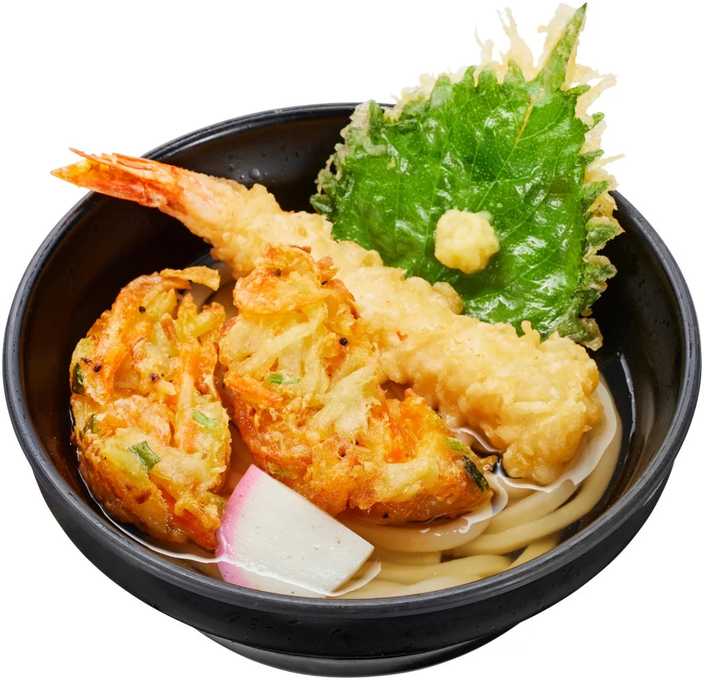 黒い器に入ったうどんで、海老天、かき揚げ、大葉の天ぷらが盛り付けられています