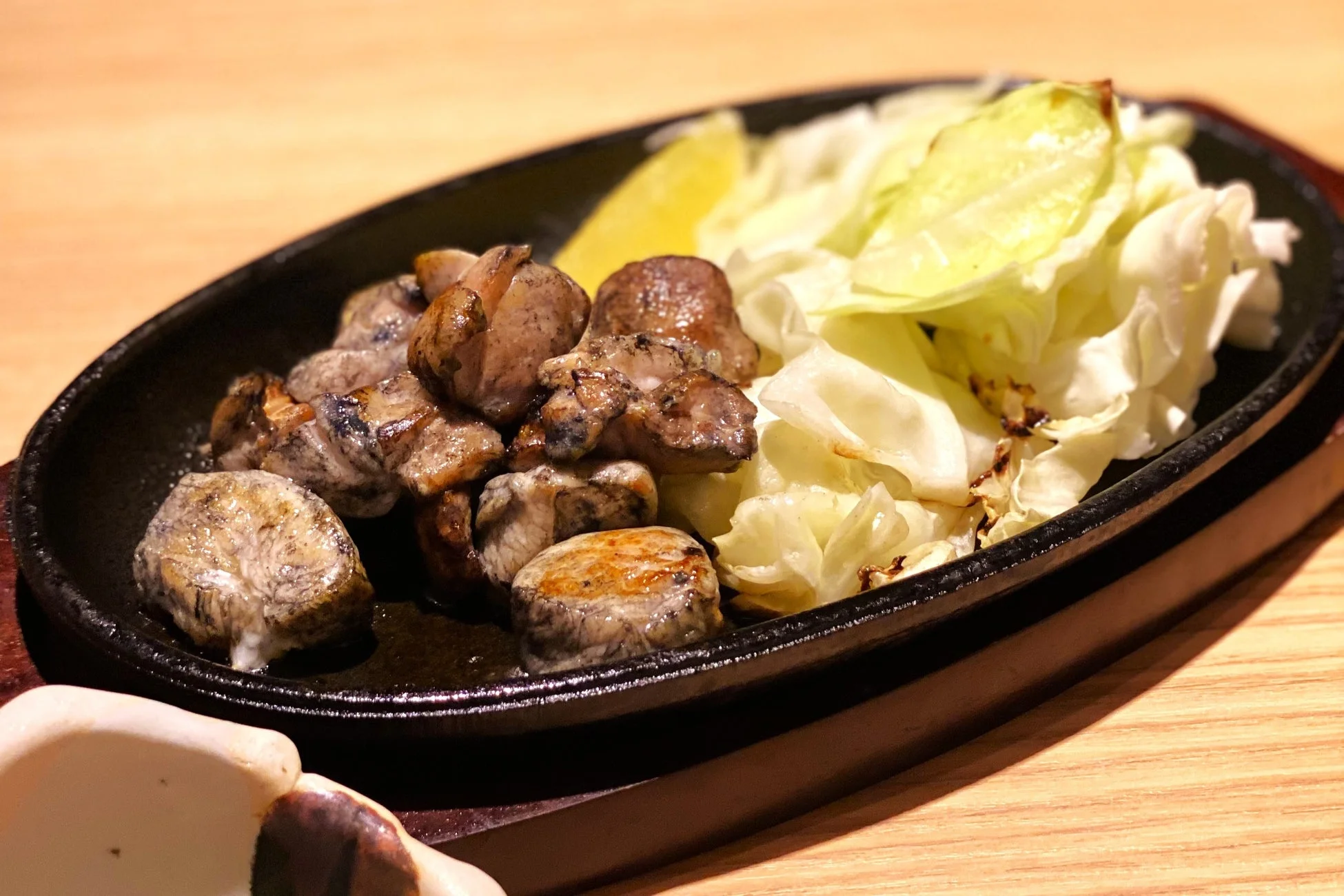 熱々鉄板で香ばしく焼かれた鶏肉とキャベツ、レモンの料理