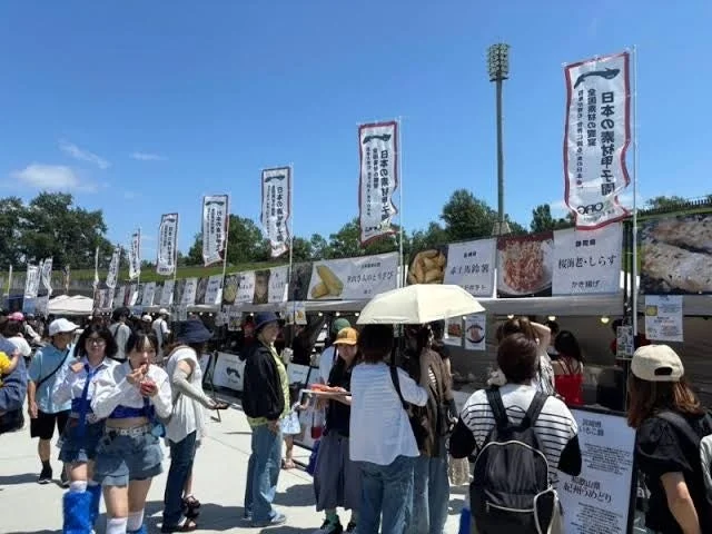 青空の下、多くの人々で賑わう屋外のフードフェスティバル