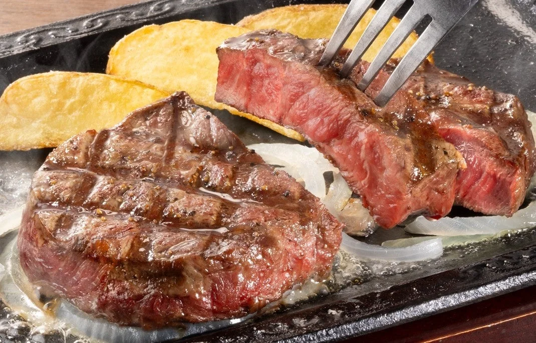 熱々の鉄板で提供されたステーキと付け合わせのポテト、玉ねぎの画像です。