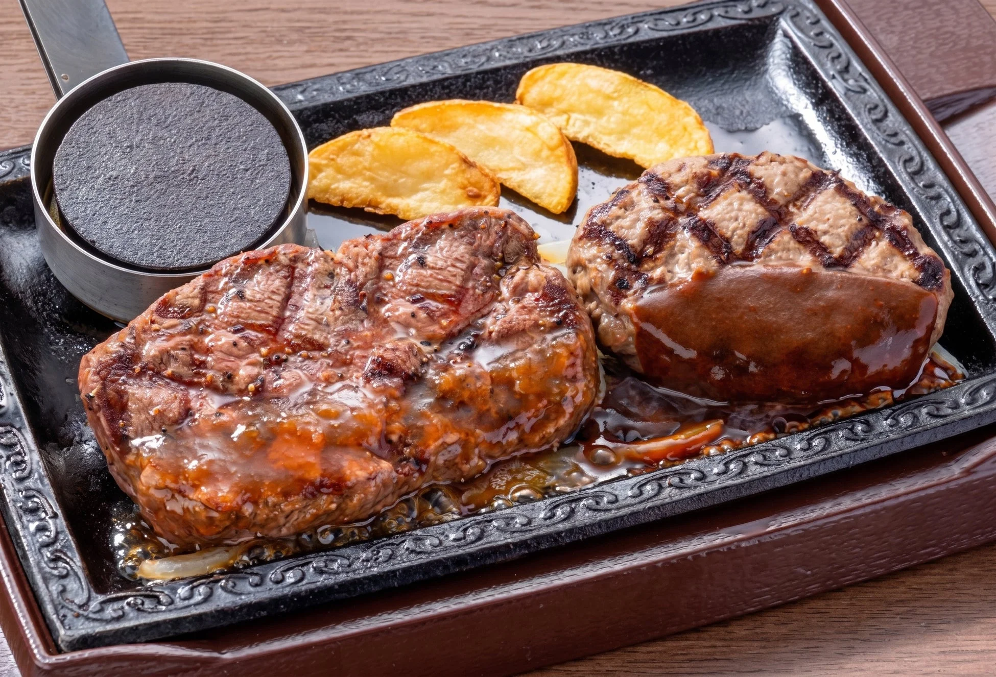 熱々の鉄板に盛り付けられたステーキとハンバーグのコンボ。
