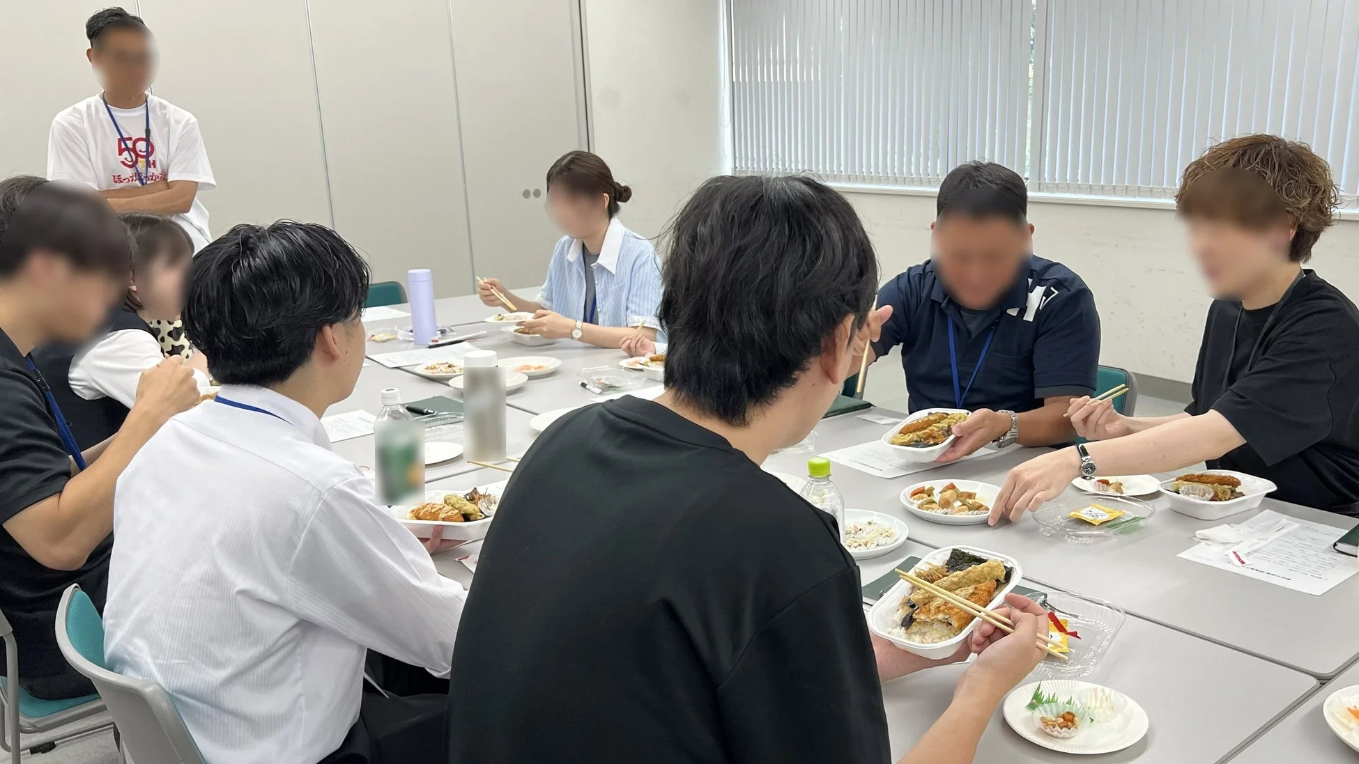 会議室で弁当を食べる人々