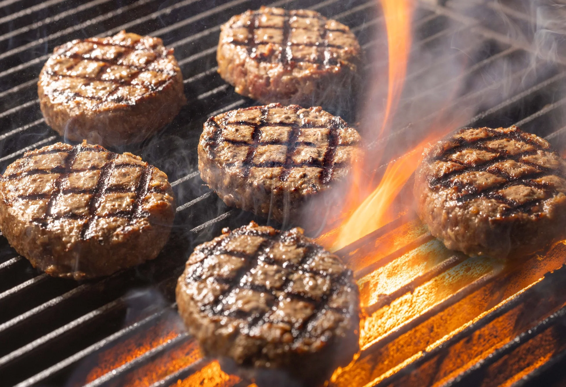 熱い網の上で複数のハンバーグが焼かれている様子です。
