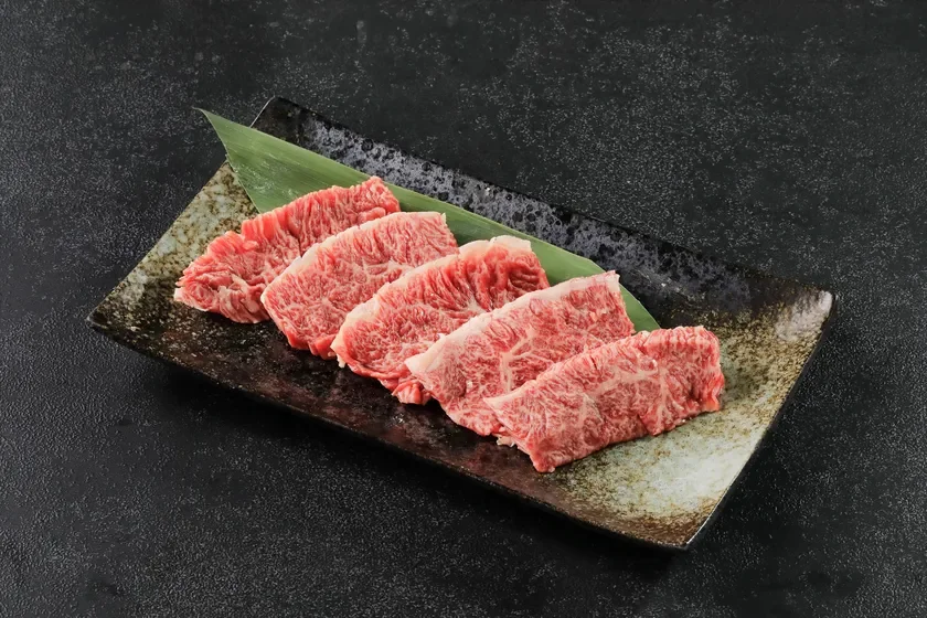 霜降りの美しい生牛肉が笹の葉を添えた陶器の皿に盛られています