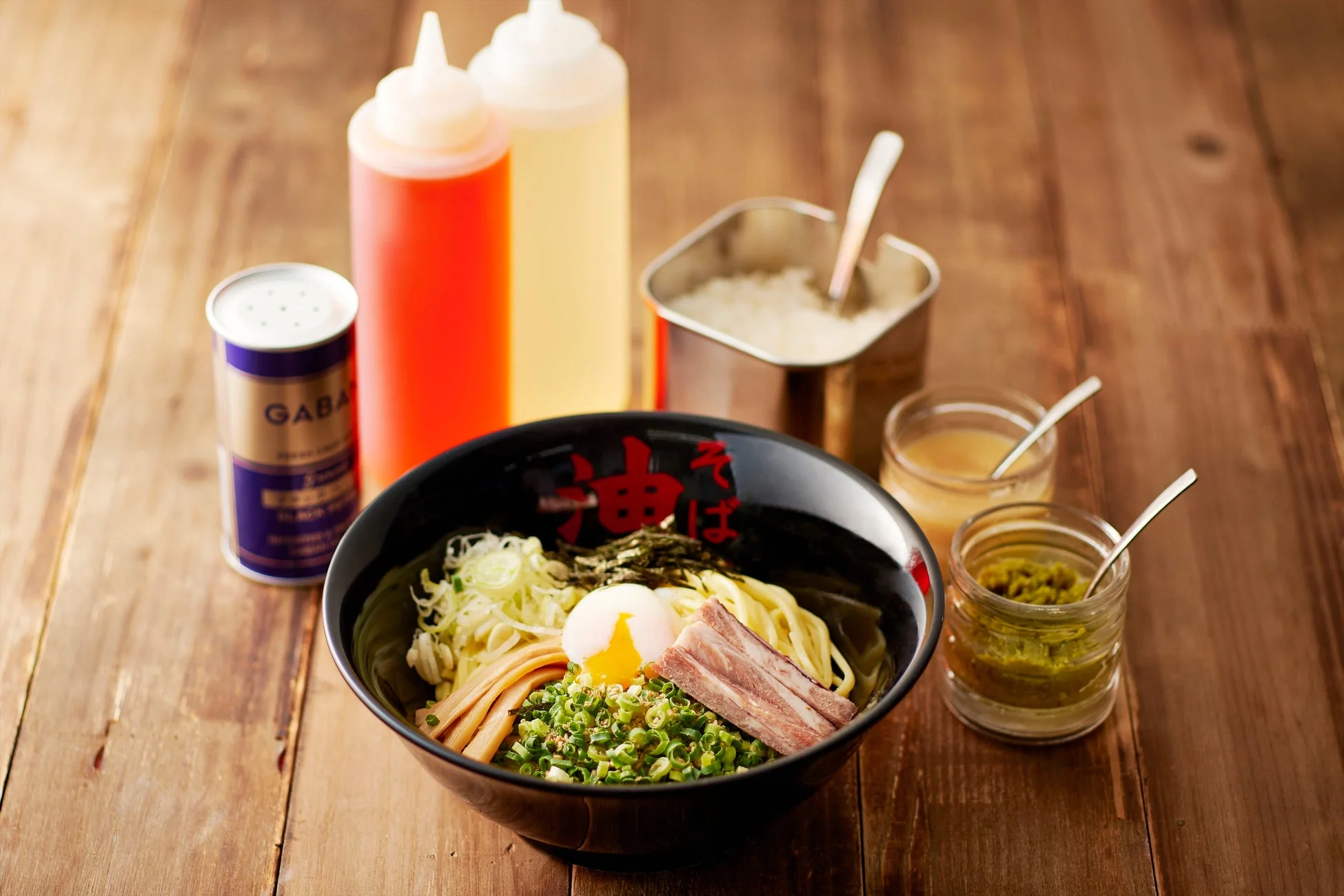油そば ラーメン 麺 和食 食べ物 半熟卵 チャーシュー ネギ メンマ 海苔 調味料 木製テーブル