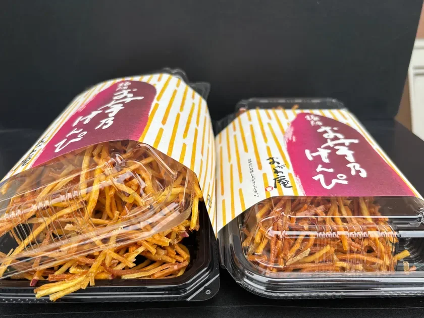 「お芋屋」の芋けんぴが2パック並べられた写真。黄金色に揚がった細長いさつまいもスティックが透明な容器にたっぷり入っており、和風のデザインが施された紙スリーブが特徴的です。