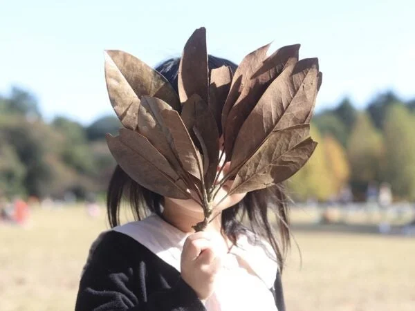 枯れ葉で顔を覆い隠す人物
