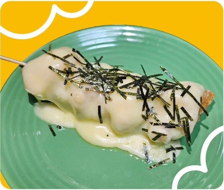 串に刺さった食べ物にチーズと刻み海苔がトッピングされている